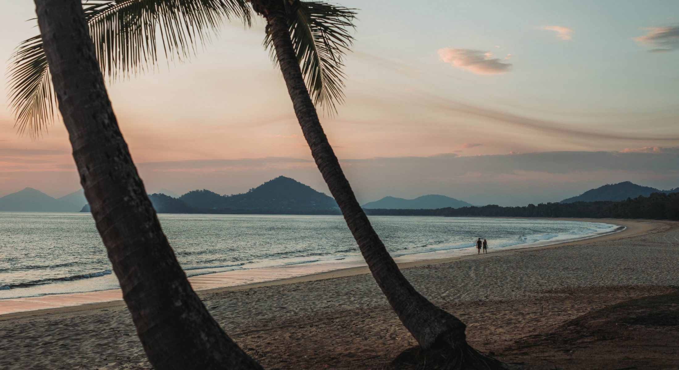Couple walking along shoreline at dusk